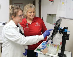 Stephanie Silver, medical lab technician, (left) and Lana James, phlebotomy technician, (right) using electronic mobile collection devices, which help standardize sample collection.